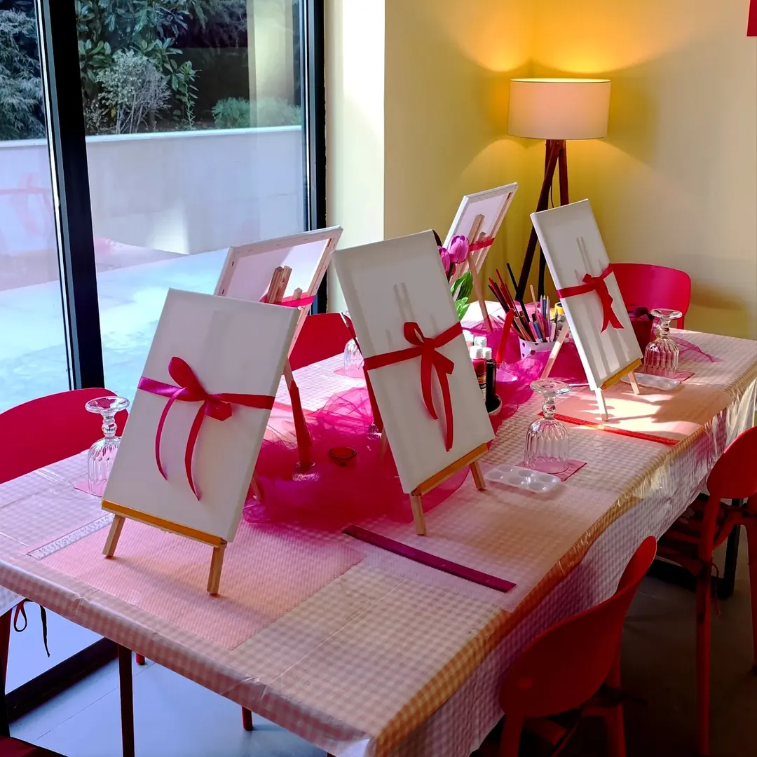 canvases on easels tied with red ribbons, along a table by the window