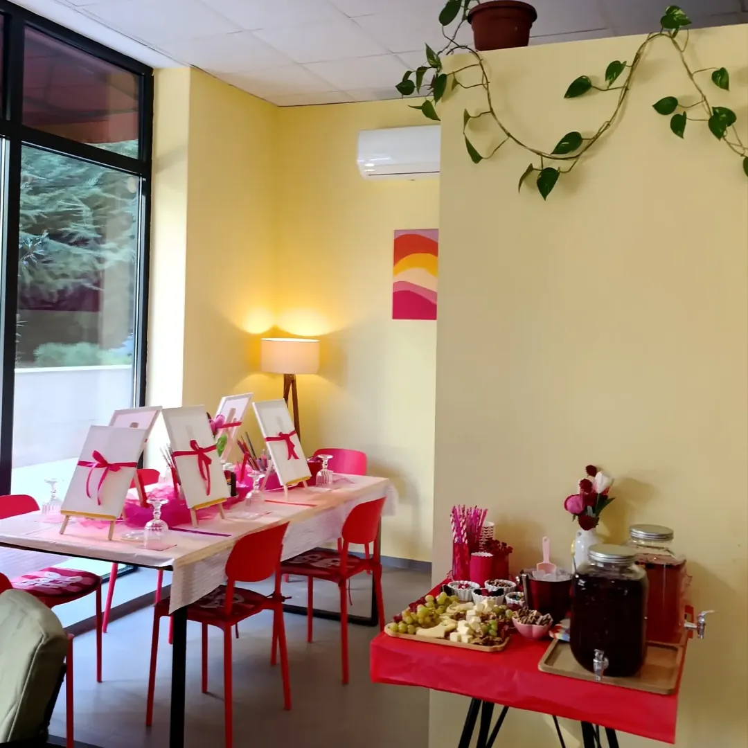 the café room: warm yellow wall, a trailing plant, a long table by the window